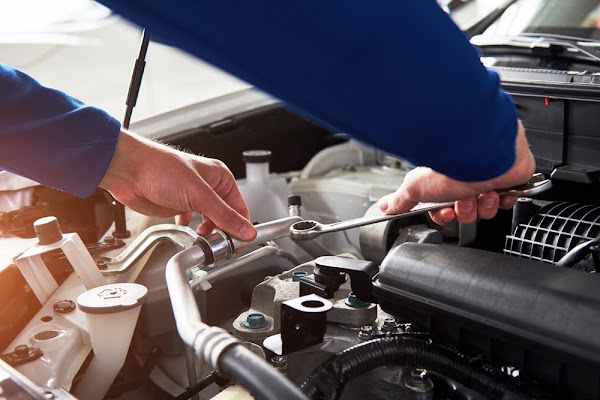 Hands of car mechanic with wrench in garage
