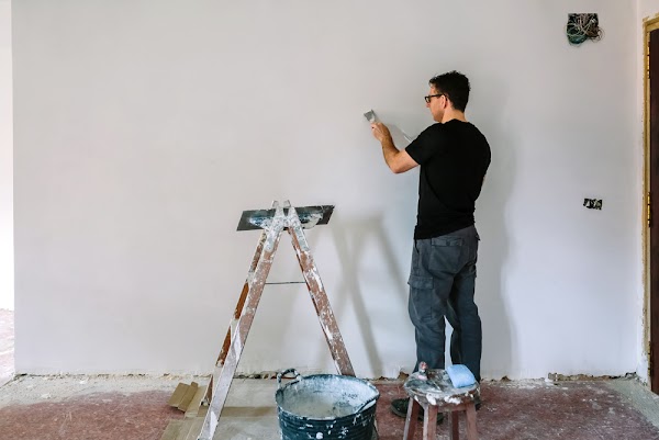 Male bricklayer repairing the wall with a spatula