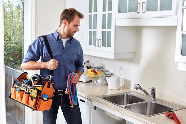 Plumber with tools doing reparation in the kitchen.